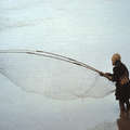 Wichí fisherman fishing in the Pilcomayo River, Argentina. The fishermen use the nets to scoop the fish up out of the muddy waters of the river.  &copy; Survival International