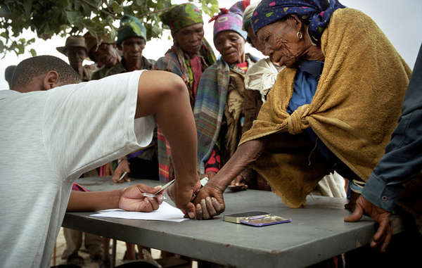 At the monthly food distribution in New Xade the mainly illiterate Bushmen sign a rosta with a thumbprint before collecting their allocated provisions.