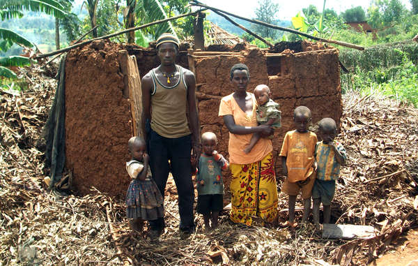 A Batwa 'Pygmy' family stand in front of their home. The roof was dismantled by local authorities under a scheme to eradicate all thatched housing in Rwanda.