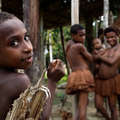 A family of the kombai tribe beneath their treehouse home &copy; Grenville Charles/Survival