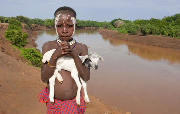 A boy from the Lower Omo stands on the riverbank.