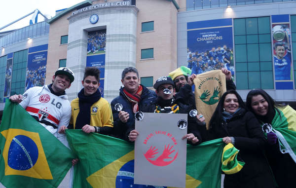 Fãs brasileiros de futebol brandindo o iconeAwá, onde se lê 'Brasil: Salve os Awá'.