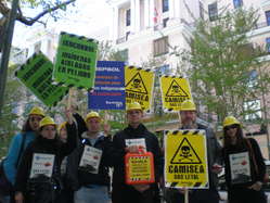 Protesters in Madrid wearing helmets and carrying placards to symbolize the lethal effects of the Camisea project on Peru's uncontacted tribes. 