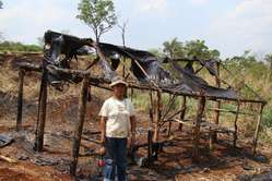 Damania, leader religieux d'Apyka'y, devant l'une des maisons incendiées.