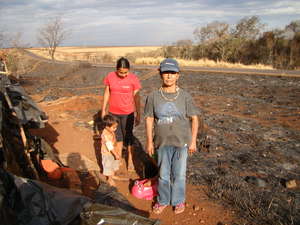 Damiana, leader of Apy Ka'y community, stands by the remains of their camp after it was destroyed by fire.