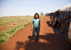 A Guarani girl stands by her road-side shack – endless fields have replaced her tribe's rich forests. Children as young as nine have been committing suicide.