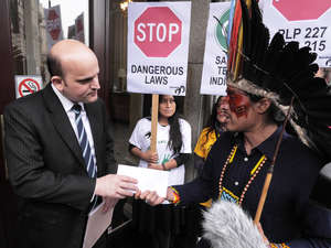 Nixiwaka Yawanawá from Brazil's Amazon hands a protest letter to an embassy official.