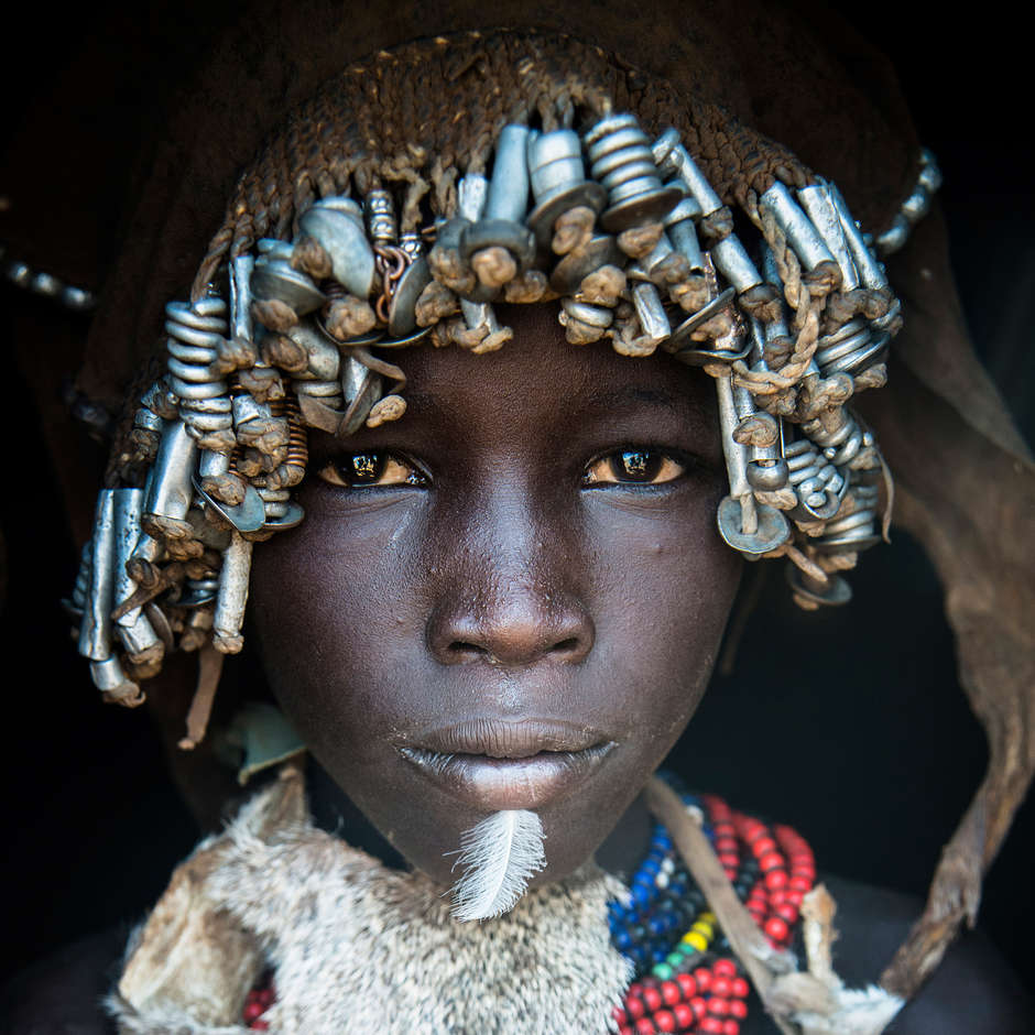 Daasanach, Ethiopia, 2014 

In Ethiopia’s Lower Omo Valley, a Daasanach boy uses feathers and metal beads as embellishments. The Daasanach are traditionally pastoral people, relying on cattle for milk, meat and hides.

Tribes living in the Omo Valley are currently at risk of losing their land to make way for plantations irrigated by a massive hydroelectric dam which is almost complete. They have not given their free, prior and informed consent to the dam or the plantations. Some tribes are being forced into resettlement camps.
