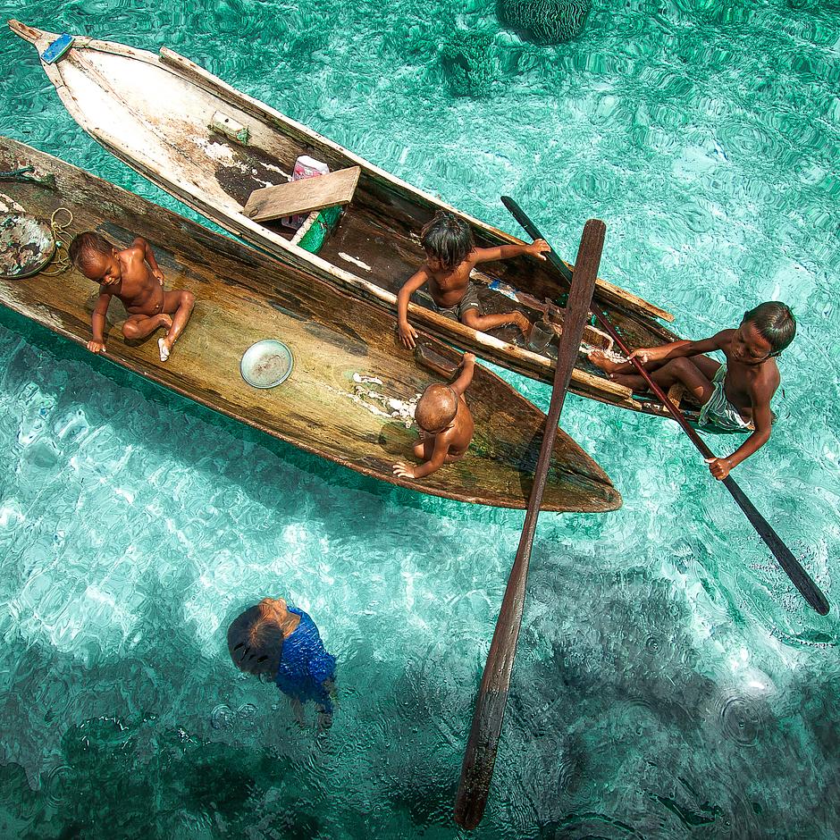 Bajau, Malaysia, 2013

Children from the Bajau tribe, otherwise referred to as ‘Sea Gypsies’, dive and play on boats floating on an azure sea. The Bajau are known for their ability to free-dive, sometimes plunging to depths of 10 to 20 meters for 5 minutes at a time to hunt fish. Some countries are trying to settle them on land.
