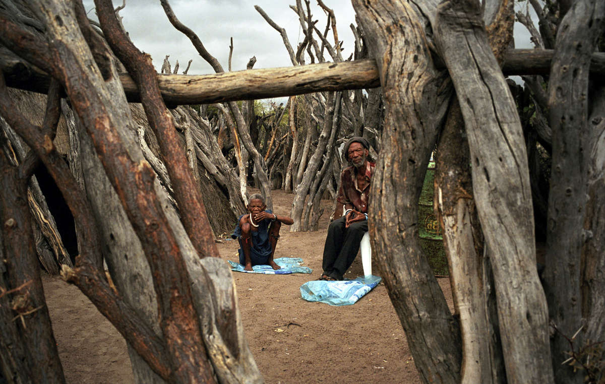 An elderly Bushman couple in their fenced yard in New Xade, the government resettlement camp to which many Bushmen have been relocated in the last ten years.