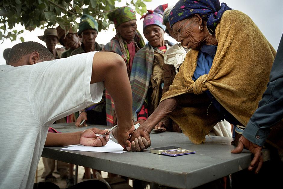 At the monthly food distribution in the New Xade, Bushmen sign a rosta with a thumbprint, before collecting their allocated food provisions.

Life in the eviction camps means the Bushmen are rarely able to earn their livelihood in the way they have for millennia, by hunting animals and gathering bush plants. Hunting is what they have always known; it is their livelihood, their history and their identity as a people. 

Now they have been denied hunting licences, and are frequently arrested and beaten when they do hunt.  One Bushman man was given a permit to enter the reserve for three days only; he was followed everywhere by armed guards.  Others have have been severely tortured by wildlife officials on suspicion of hunting.

‘The Bushmen are a hunting people,’ said Roy Sesana.  ‘I grew up a hunter. All our boys and men were hunters.’

In the eviction camps, however, they are dependent on government hand-outs.  

‘I do not want this life,’ says  a Gana Bushman. ‘First they make us destitute by taking away our way of life, then they say we are nothing because we are destitute.’