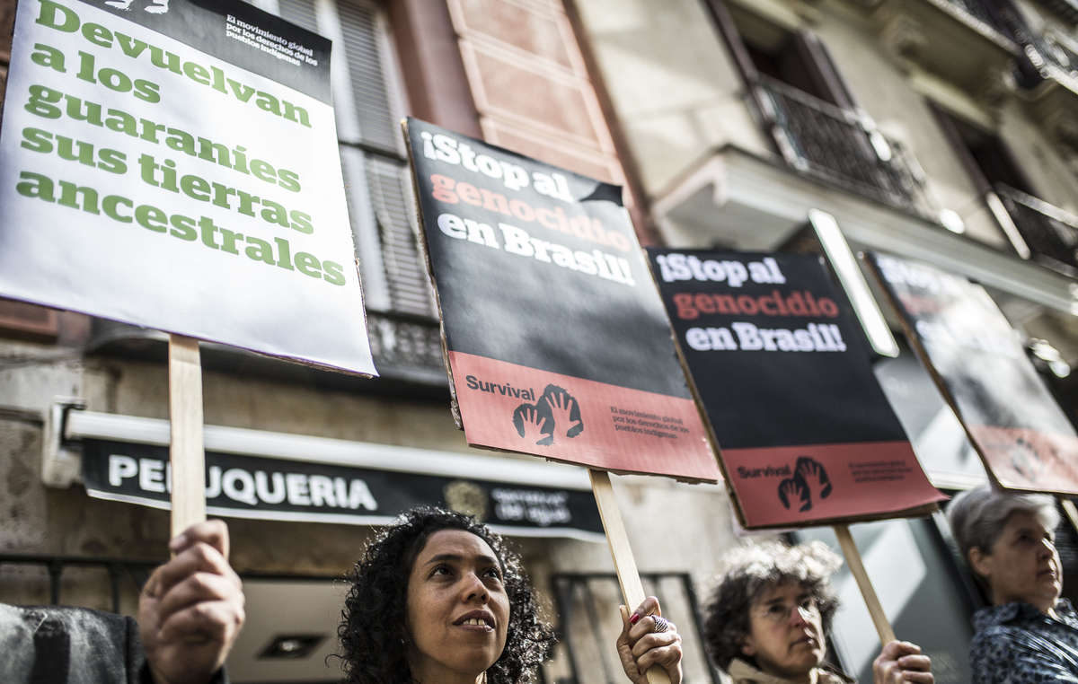 Activistas portan pancartas contra el robo de tierras indígenas ante la Embajada de Brasil en Madrid.