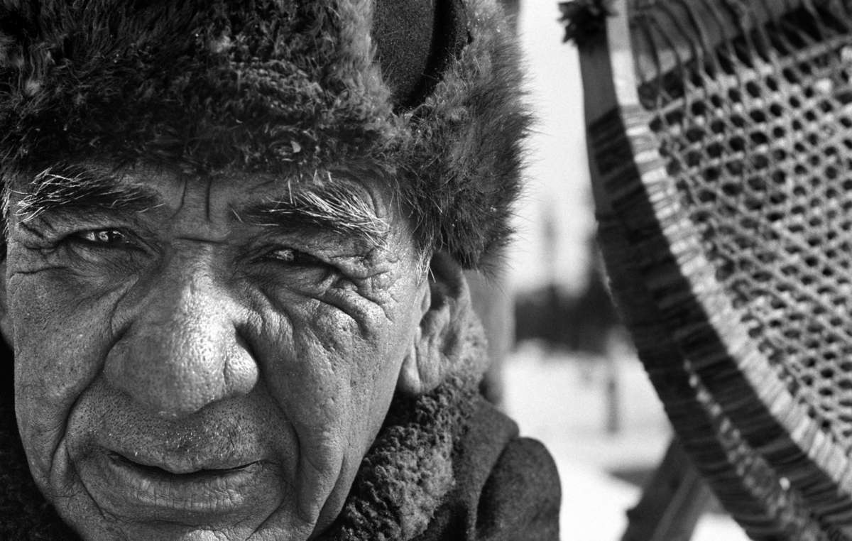 Elder Shoashim Nui, le charpentier le plus habile de la communauté devant une paire de ses fameuses raquettes de neige.