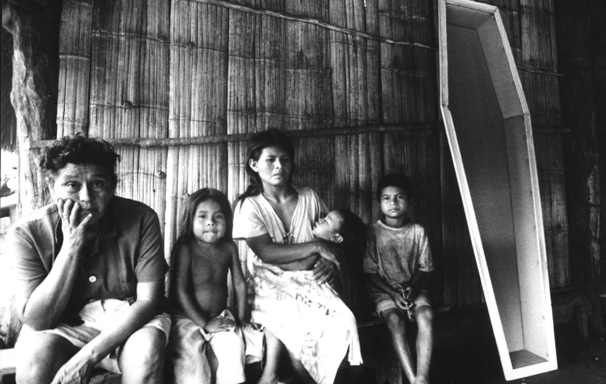 Eine brasilianische Guarani-Familie sitzt neben einem Sarg