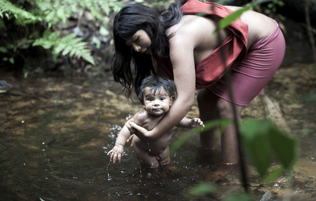 Awá-Guajá mother and child bathing in the river, Brazil.