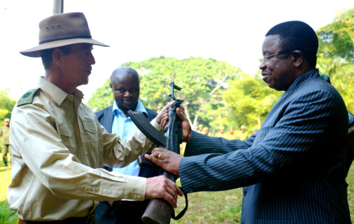 Oficiais congoleses entregam um rifle ao funcionário de alto cargo (e funcionário do WWF local) do Parque Nacional de Salonga. Alguns guardas do parque foram acusados de estupro coletivo, tortura e assassinato.