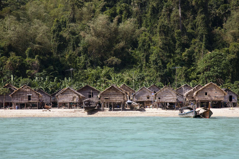 Ein Dorf der Moken auf einer der Surin Inseln.

Die Häuser wurden nach dem Tsunami 2004 von der thailändischen Regierung gebaut, nachdem viele _Kabang_ der Moken zerstört worden waren. Heute gibt es nur noch wenige _Kabang_ in dem Dorf, viele der Boote sind nun typische thailändische Langboote. Die Entwicklungen nach dem Tsunami haben auch bewirkt, dass viele der Familien den Zugang zu ihren Fischgründen verloren haben. 

Die Moken der Mergui Inselgruppe sehen sich vielen Problemen gegenüber: Von Diskriminierung (viele Thailänder betrachten sie als „rückständig“) und Assimilierung, bis zur Gefahr von Burmas Grenzhütern angeschossen oder festgenommen zu werden. Viele Moken verfallen dem Alkohol, der größtenteils von Touristen eingeführt wird. Eine stärkere Abhängigkeit von Konsumgütern hat auch dazu geführt, dass die Moken von der Geldwirtschaft abhängig geworden sind. 

Die Trennung von ihrem angestammten Lebensraum ist häufig ein Grund für körperliche und seelische Erkrankungen unter den Moken. „Die Familien in den permanenten Dörfern sind verloren,“ sagt Pe Tat. „Sie wissen nicht mehr wohin mit sich selbst. Das Leben das sie bisher kannten ist weg. Sie sind gelangweilt, deswegen verfallen sie dem Alkohol.“

Narumon Arunotai zufolge hat die Abhängigkeit bereits viele Männer der Moken getötet. „Das führt dazu, dass die Frauen noch größere Bürden zu tragen haben, da sie für den zurückgelassenen Haushalt aufkommen müssen,“ erklärt Arunotai.