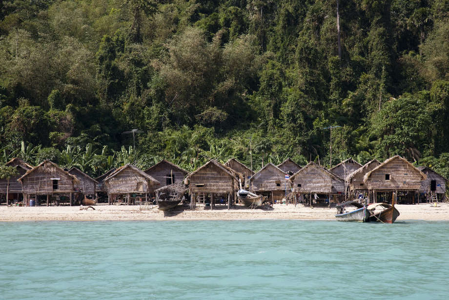 Ein Dorf der Moken auf einer der Surin Inseln.

Die Häuser wurden nach dem Tsunami 2004 von der thailändischen Regierung gebaut, nachdem viele _Kabang_ der Moken zerstört worden waren. Heute gibt es nur noch wenige _Kabang_ in dem Dorf, viele der Boote sind nun typische thailändische Langboote. Die Entwicklungen nach dem Tsunami haben auch bewirkt, dass viele der Familien den Zugang zu ihren Fischgründen verloren haben. 

Die Moken der Mergui Inselgruppe sehen sich vielen Problemen gegenüber: Von Diskriminierung (viele Thailänder betrachten sie als „rückständig“) und Assimilierung, bis zur Gefahr von Burmas Grenzhütern angeschossen oder festgenommen zu werden. Viele Moken verfallen dem Alkohol, der größtenteils von Touristen eingeführt wird. Eine stärkere Abhängigkeit von Konsumgütern hat auch dazu geführt, dass die Moken von der Geldwirtschaft abhängig geworden sind. 

Die Trennung von ihrem angestammten Lebensraum ist häufig ein Grund für körperliche und seelische Erkrankungen unter den Moken. „Die Familien in den permanenten Dörfern sind verloren,“ sagt Pe Tat. „Sie wissen nicht mehr wohin mit sich selbst. Das Leben das sie bisher kannten ist weg. Sie sind gelangweilt, deswegen verfallen sie dem Alkohol.“

Narumon Arunotai zufolge hat die Abhängigkeit bereits viele Männer der Moken getötet. „Das führt dazu, dass die Frauen noch größere Bürden zu tragen haben, da sie für den zurückgelassenen Haushalt aufkommen müssen,“ erklärt Arunotai.
