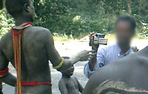 A tourist films a Jarawa man up close on the road. Campaigners have raised deep concerns about the dangerous, degrading and exploitative nature of tribal tourism.