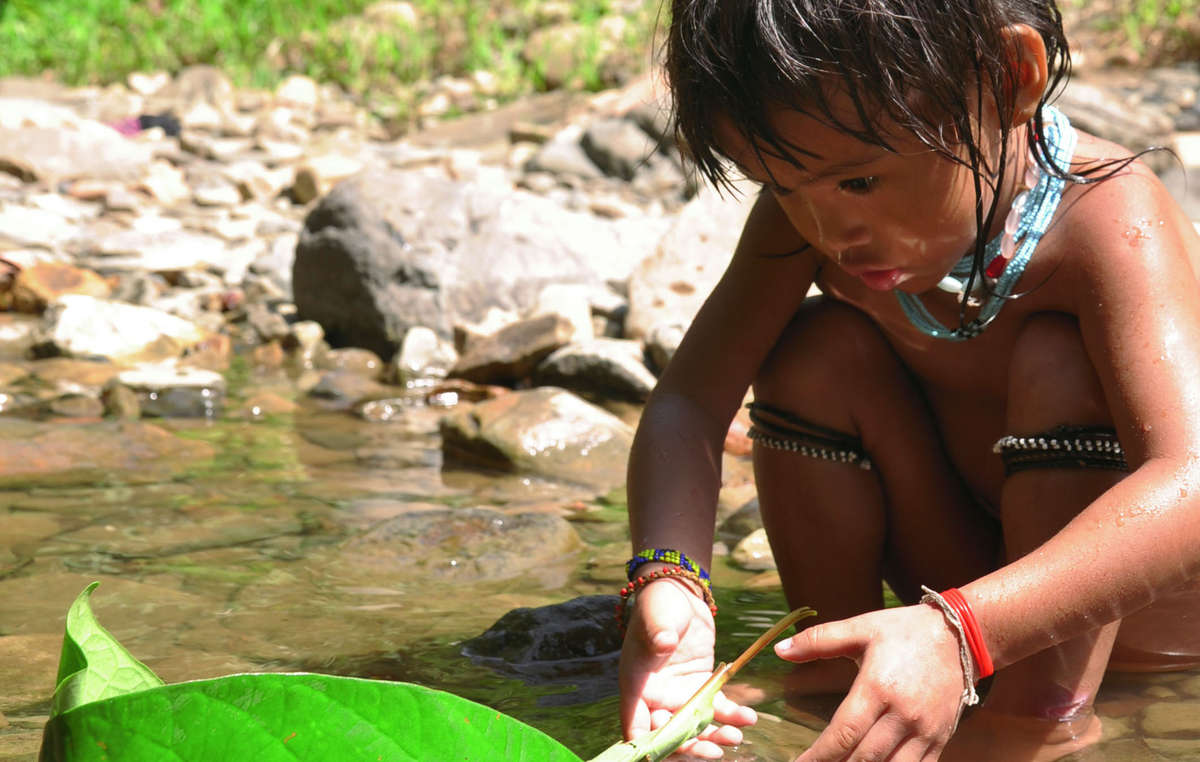 Ein Penan-Kind spielt an einem Fluss mit einem selbstgebauten Boot. Staudämme in der Region bedrohen das Überleben der Penan.