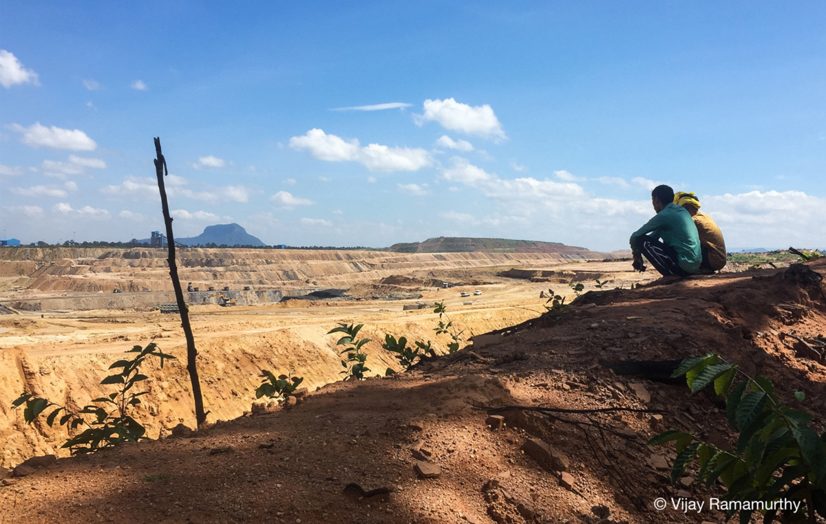 Due uomini Adivasi osservano un paesaggio apocalittico, la grande miniera di carbone che ha preso il posto della loro foresta ancestrale, Hasdeo, Chhattisgarh, India.