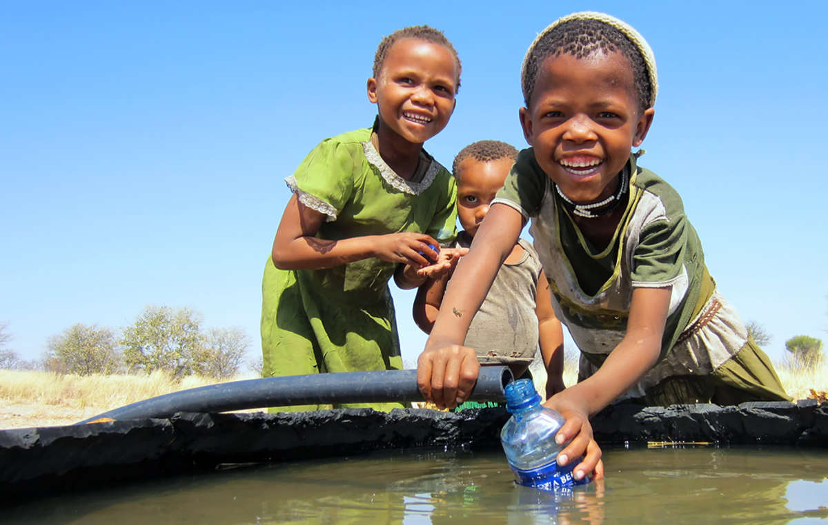 Bushmen girls playing with water from the Mothomelo borehole on the Central Kalahari Game Reserve, Botswana.