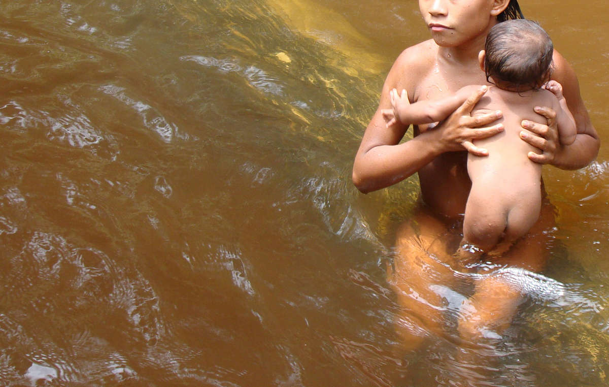 Ein Suruwaha-Junge badet ein Baby im Wasser.