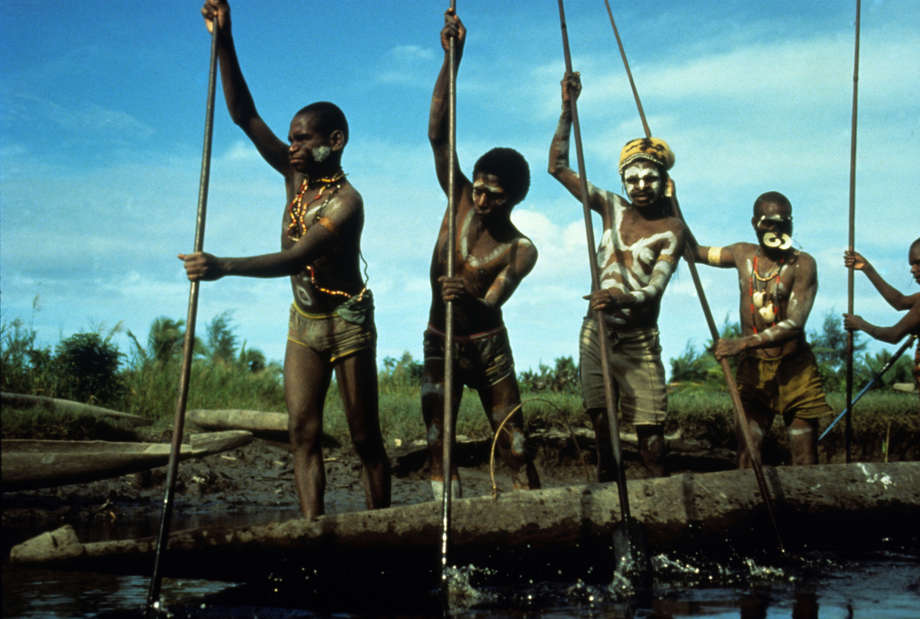 In southern Papua, a few degrees south of the Equator, there are no roads in the coastal homeland of the semi-nomadic Asmat people.

As a result, the Asmat have long used canoes to journey along the extensive network of deep, wide rivers that run through their rainforest. 

Canoeists propel and steer while standing, their skill lying in maintaining their balance as they dip and sweep long tassled blades through the tidal waters; a particularly difficult and dangerous task when cross-currents are created from rivers flowing into the Arafura Sea.

All Papuan tribal peoples have suffered greatly under the Indonesian occupation, which began in 1963, and is almost unparalleled in its brutality.
