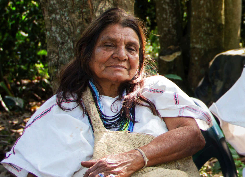 „Ich bin die Witwe von Angel María Torres“, sagte Dilia Torres, als sie eine Mitarbeiterin von Survival International begrüßte, die durch die Berge gewandert war, um ihr Arhuaco-Dorf zu erreichen. 

Im November 1990 hatten sich Angel María Torres und zwei weitere Arhuaco-Anführer auf der Reise aus ihrer Heimat in der nördlichen Sierra Nevada in Kolumbiens Hauptstadt Bogotá befunden.

Sie kamen nie zurück. In Ruhe erzählt Dilia, eine warmherzige, lächelnde Frau, ihre tragische Geschichte.

„Zehn Tage später erfuhren wir, dass mein Mann nie in Bogotá angekommen war. Angel und die anderen Männer waren festgenommen, gefoltert und getötet worden. Als sie meinen Mann gefunden haben, fehlten ihm die Haare und die Finger.“

„Ich habe alle Hoffnung auf ein Leben mit Partner und Familie verloren. Ich denke, dass indigene Völker auch weiterhin ohne jegliche Hoffnung auf Gerechtigkeit ins Visier genommen werden.“

„So ist es jetzt. Wir haben gelernt in Ruhe und in ständiger Angst zu leben. Aber wir sind Arhuaco. Also sollten sie uns wir Arhuaco behandeln.“