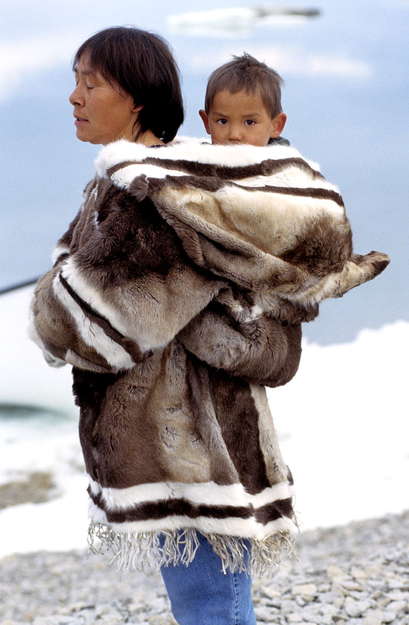Inuit infants are carried  by their mothers in an _amautik_ for the first year or two of their lives. 

An _amautik_ was traditionally made from caribou fur, with the fur facing in, so the baby lay in its comfort and warmth. Today, they are also made from duffel and other materials.

'After feeding, the baby girl dozes. With words of welcome, she is lifted into the _amautik_, the pouch shaped into the hood of her mother's parka, where she can lie curved against her mother's back. The baby's mother smiles, holding her daughter for her father to adore, and says, 'Anaanangai. Ii, anaanagauvutit.' 'Mother? Yes, you're my mother.' ... For she is a baby who carries the _atiq_, the spirit and name, of her late grandmother.'

Hugh Brody, from _The Other Side of Eden: Hunters, Farmers, and the Shaping of the World_.