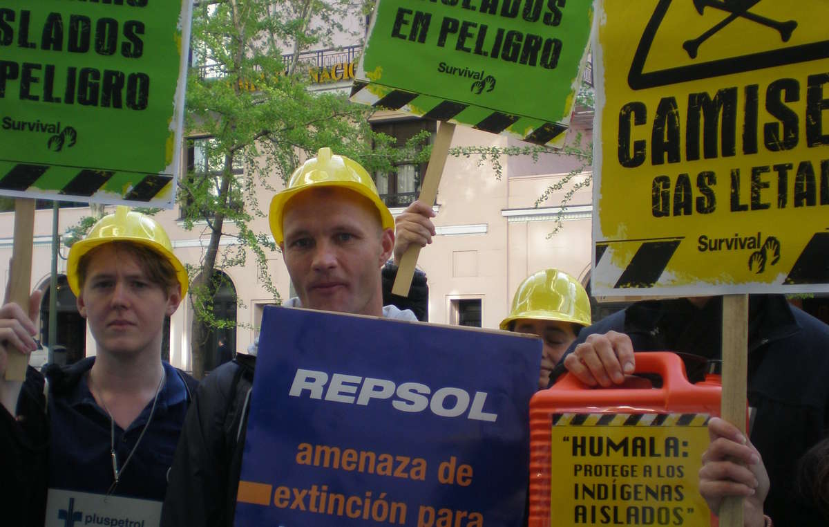 Manifestantes en Madrid con pancartas y cascos de obra denuncian las consecuencias letales de Camisea para los indígenas aislados.