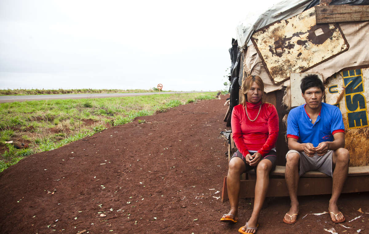 Ein Guarani-Kaiowa-Paar sitzt vor seiner behelfsmäßigen Straßensiedlung in Apy Ka’y, in der Nähe von Dourados, Mato Grosso do Sul, Brasilien.