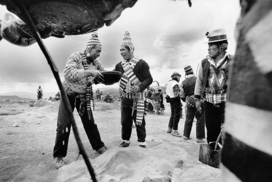 Auf dem weiten und stürmischen Plateau der zentralen Anden in Bolivien trinken Aymara-Indigene während eines Festes Chicha, ein Getränk, das aus Mais und rotem Pfeffer gemacht wird.