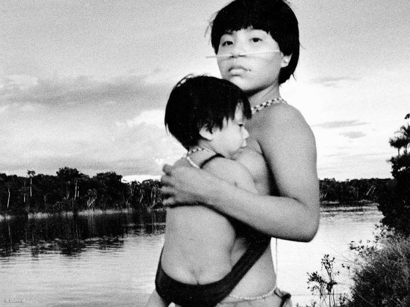 A Yanomami woman and child on the banks of an Amazonian river.

_For many tribal societies, childbirth is usually regarded as an everyday event, attracting no fanfare, with little special attention given to either baby or mother_, says Stephen Corry, Director of Survival International.

Yanomami women normally leave their _shabono_ (communal houses), accompanied by their mothers or other older female relatives, in order to give birth in the rainforest.  Most Yanomami women carry their child in a sling, made from cotton or strips of a fiber plant such as banana, for up to two years.

They breastfeed their children until they are several years old, a practice which is known to inhibit conception.  