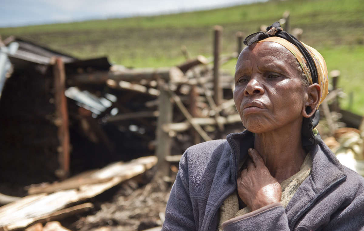 An Ogiek woman sits in front of the remains of her demolished house.