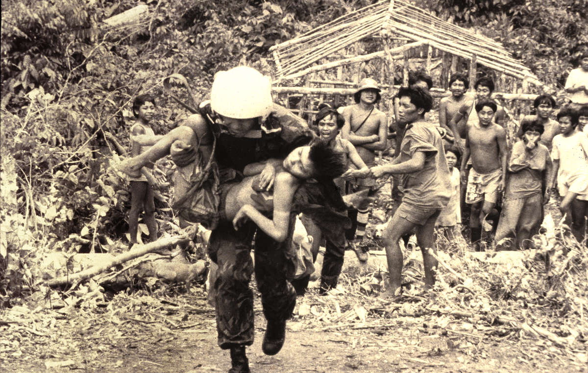 Tra il 1986 e il 1992, la terra yanomami fu invasa da oltre 40.000 cercatori d’oro che portarono con sé la malaria e altre malattie verso cui gli Indiani non avevano difese immunitarie. Morì il 20% della popolazione. La donna nella foto fu una delle tante persone portate via in elicottero.