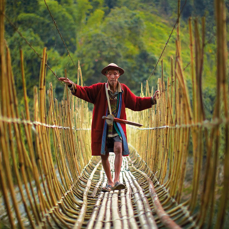 März 2015:  Adi-Mann, Arunachal Pradesh, Indien.

Ein älterer Adi-Mann überquert vorsichtig eine Bambus-Brücke.